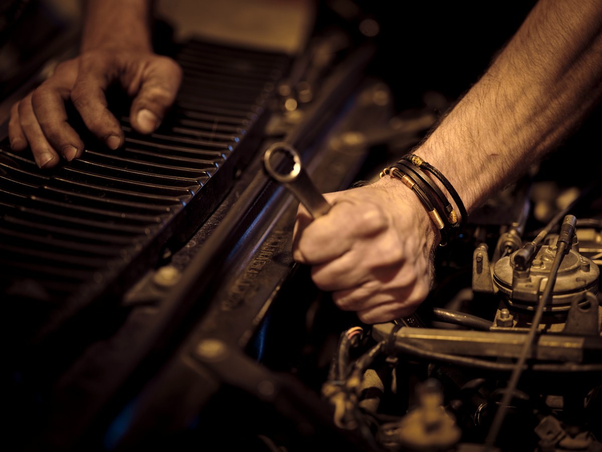 Mani di un meccanico che lavorano sul motore con una chiave inglese